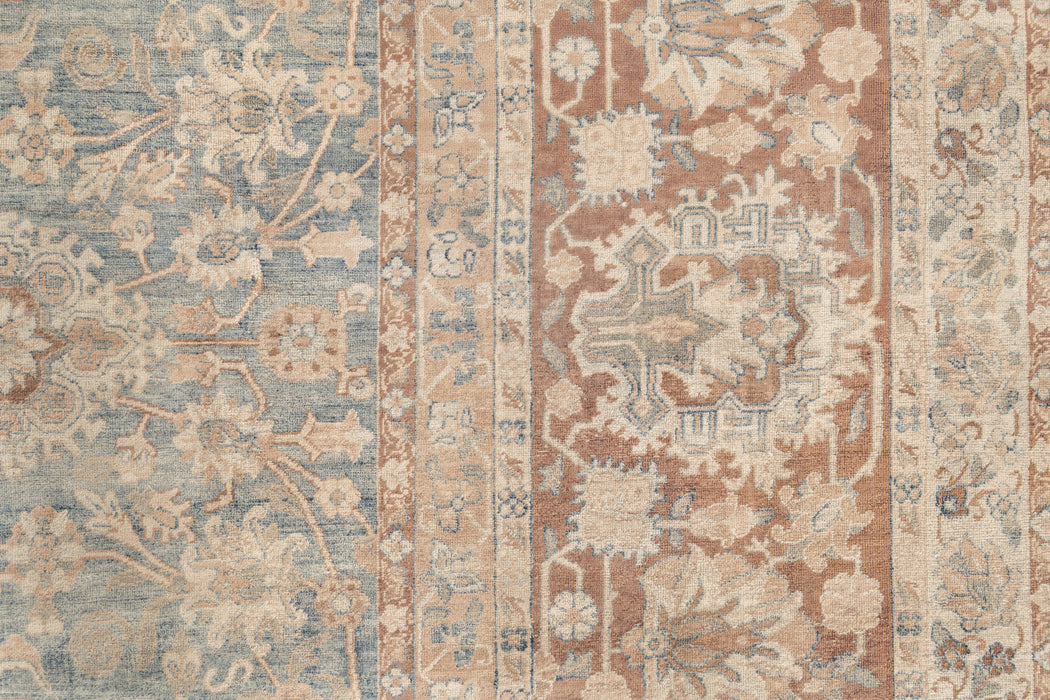 A close-up image of a vintage, intricately patterned heirloom KERMAN RUG, SOUTH EAST PERSIA, 10' 8" X 14' 8". The rug by Ben Soleimani features a combination of light blue and beige tones with detailed floral and geometric designs. The pattern includes various floral motifs and ornate shapes arranged in vertical strips, showcasing its museum-quality craftsmanship.