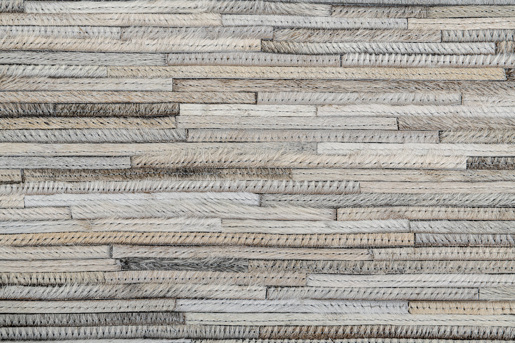 A textured wall made of interlocking wooden strips in varying shades of gray and beige creates a rustic and natural look. The wood appears to have a rough, unfinished surface, adding to the overall rugged aesthetic, reminiscent of pieces from the Ben Soleimani collection.